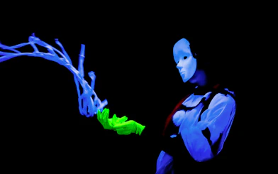 Performer in black light theatre, Prague, with glowing mask and gloves.