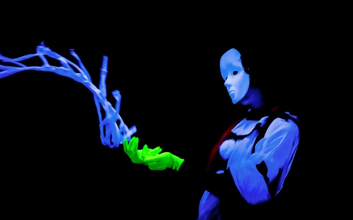 Performer in black light theatre, Prague, with glowing mask and gloves.