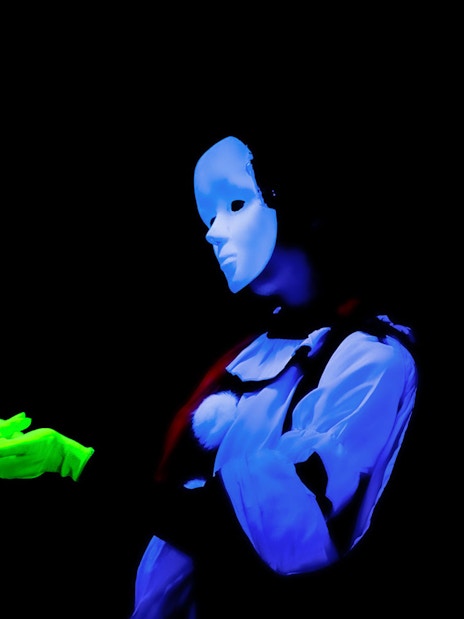 Performer in black light theatre, Prague, with glowing mask and gloves.
