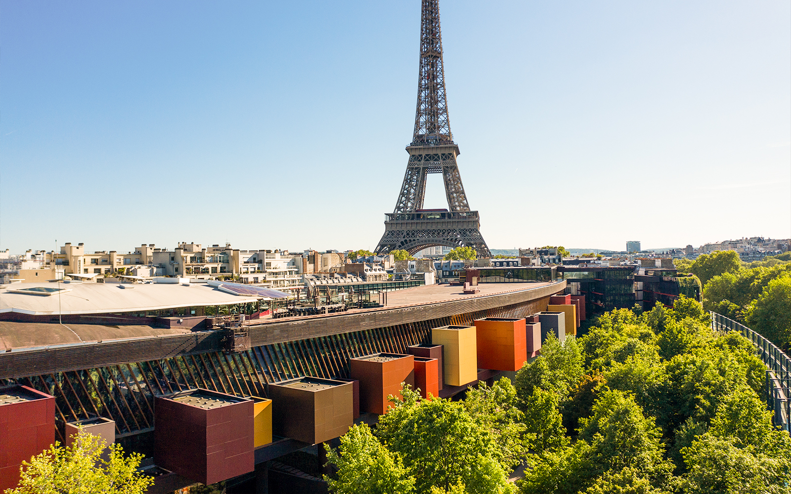 Eiffel Tower view from Musée du Quai Branly, Paris, with colorful museum facade and trees.