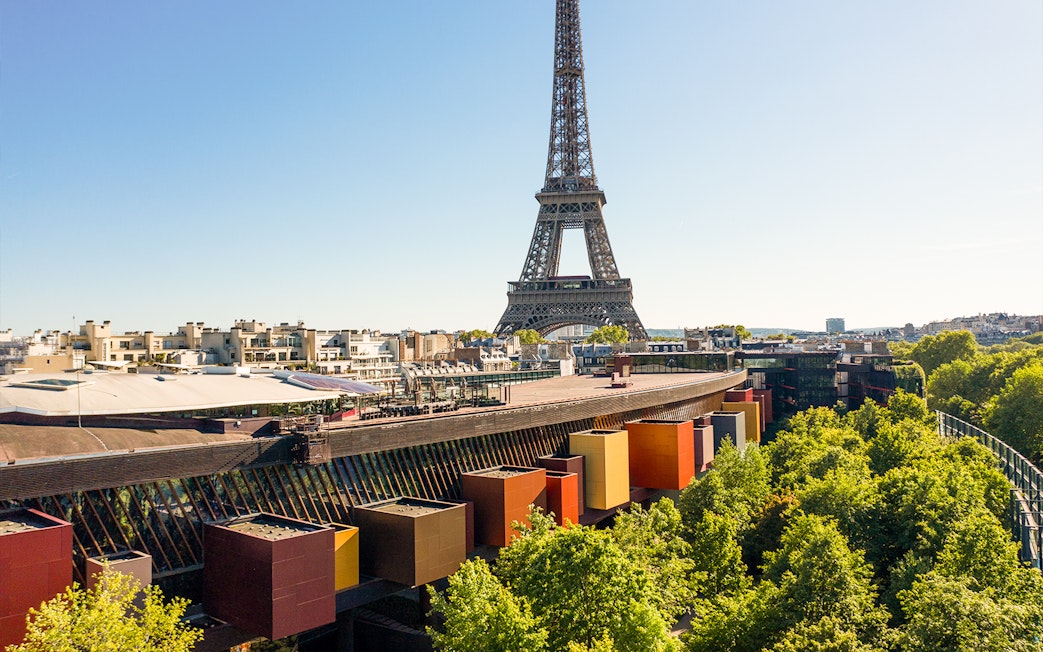 Eiffel Tower view from Musée du Quai Branly, Paris, with colorful museum facade and trees.