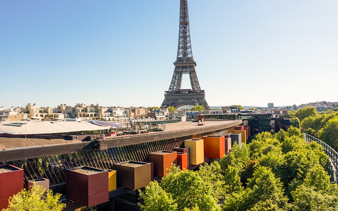 Eiffel Tower view from Musée du Quai Branly, Paris, with colorful museum facade and trees.