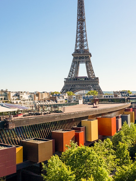 Eiffel Tower view from Musée du Quai Branly, Paris, with colorful museum facade and trees.