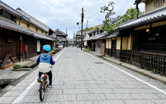 Cyclist on e-bike tour through traditional street in Asuka, Nara.