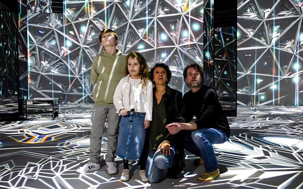 Family exploring digital art installation at Journey Exhibit, Port des Lumières, Hamburg.