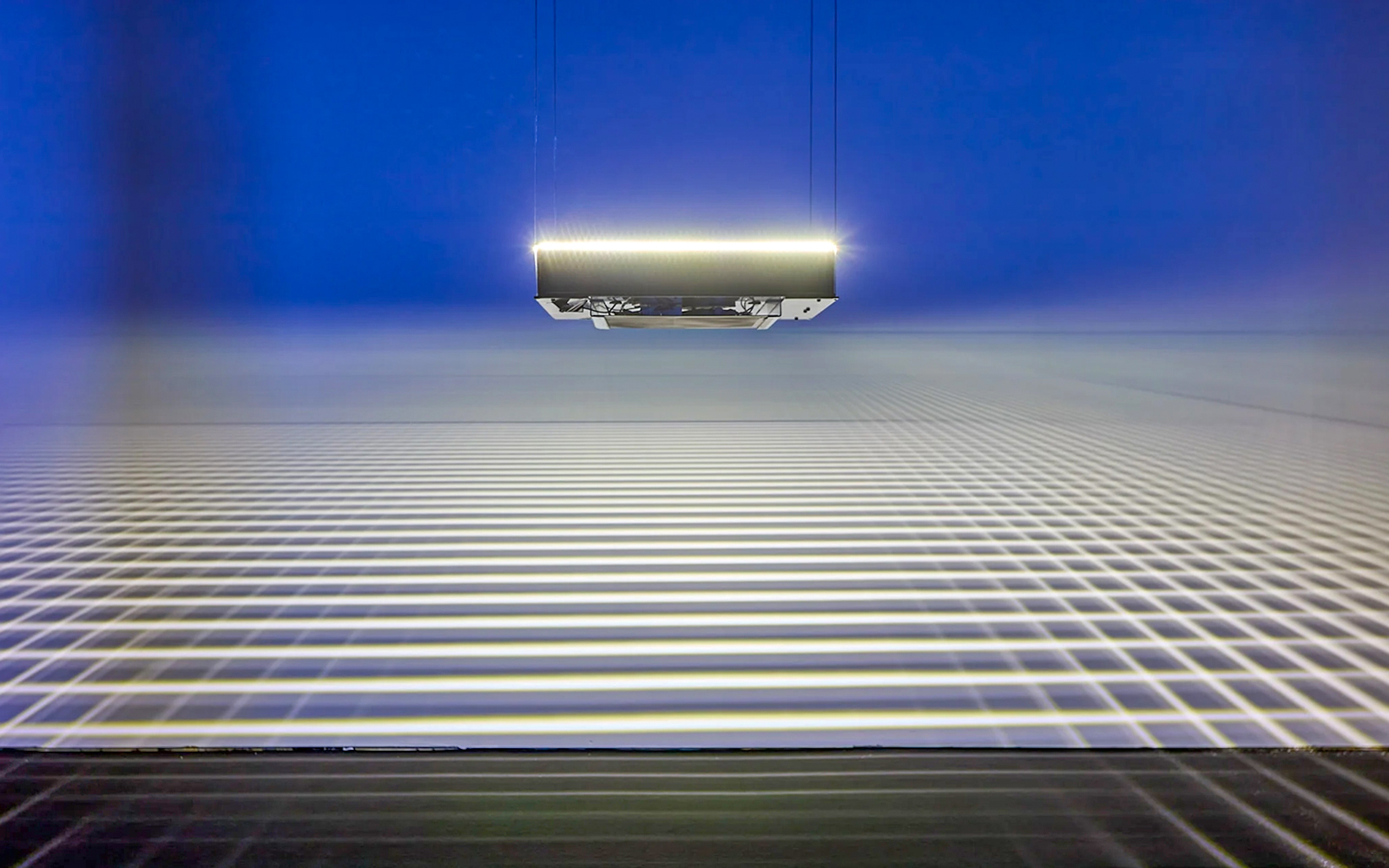 Suspended light installation casting grid patterns at Light Art Museum exhibit.