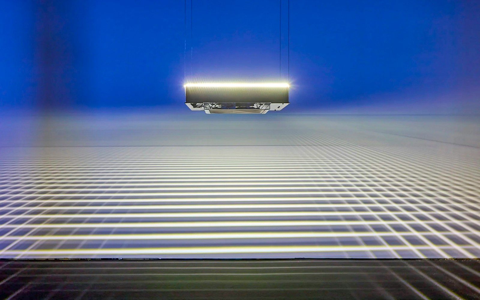 Suspended light installation casting grid patterns at Light Art Museum exhibit.