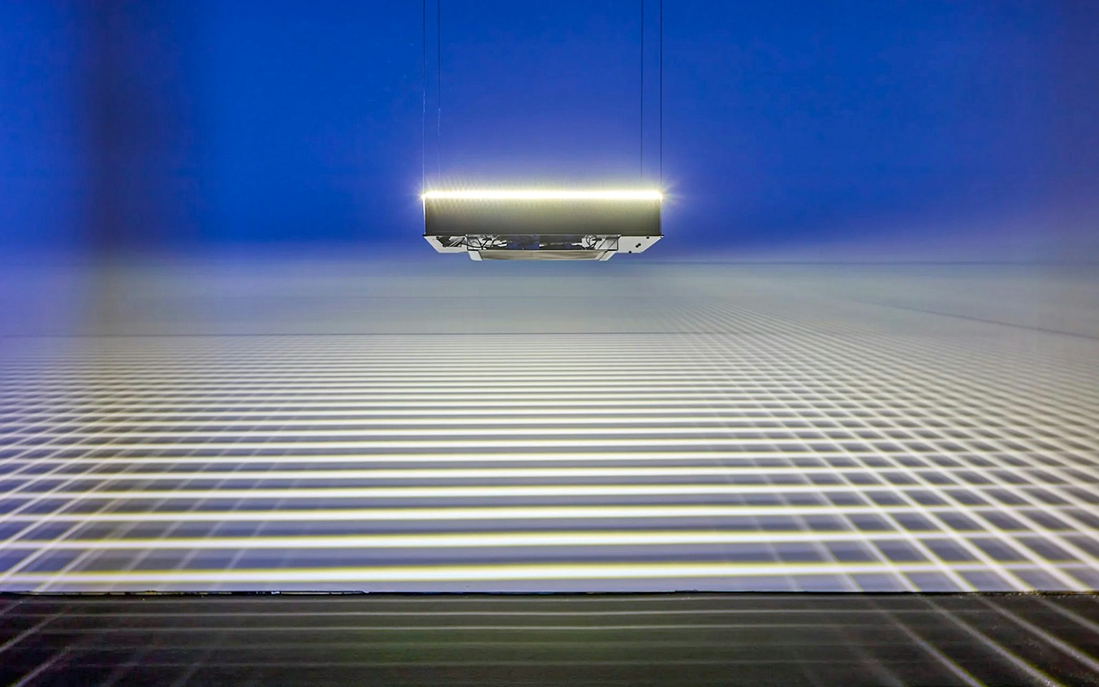 Suspended light installation casting grid patterns at Light Art Museum exhibit.