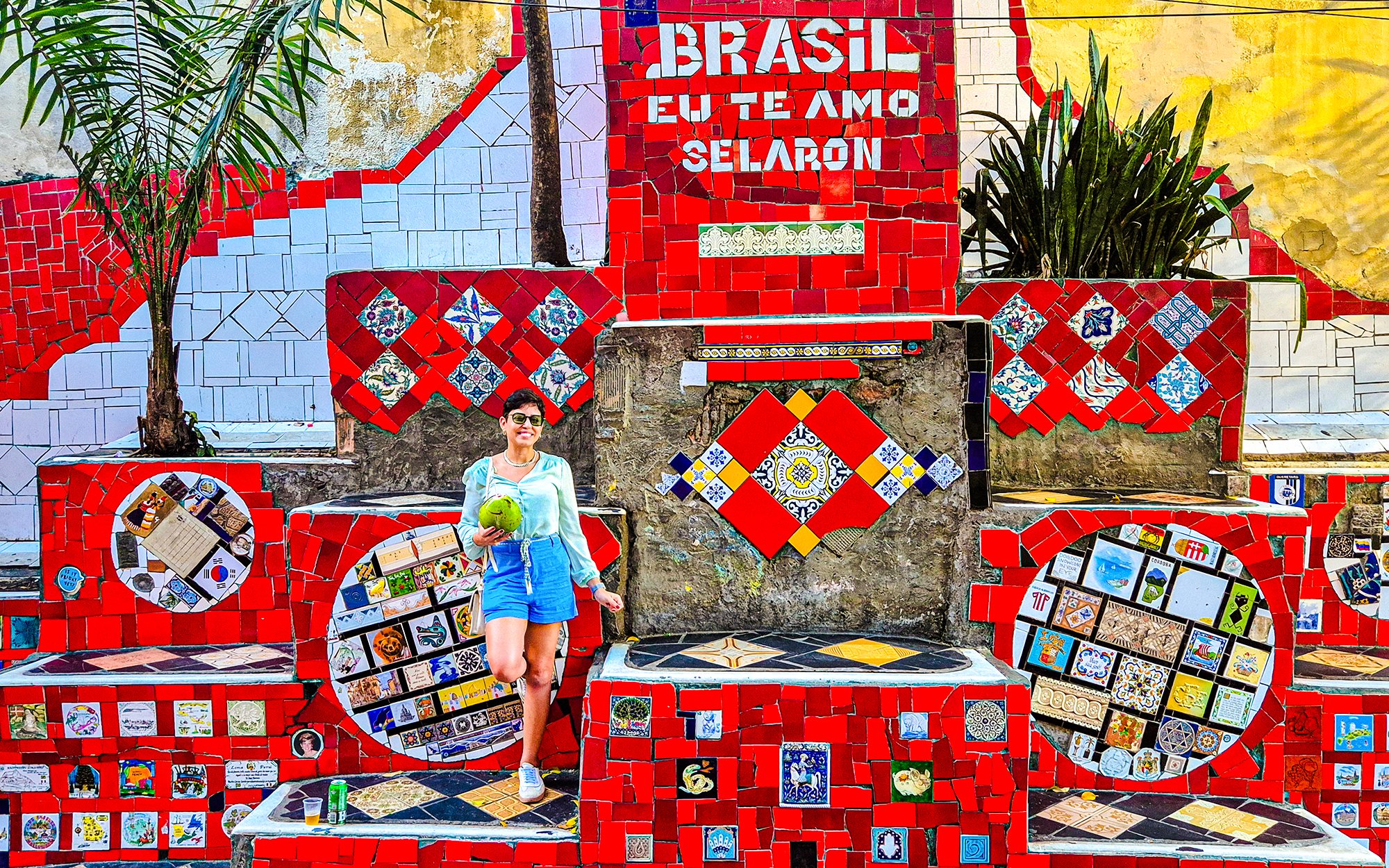 Tourist holding coconut at colorful Selaron Steps in Rio de Janeiro, Brazil.