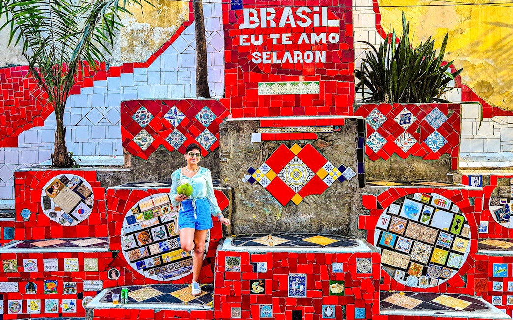 Tourist holding coconut at colorful Selaron Steps in Rio de Janeiro, Brazil.