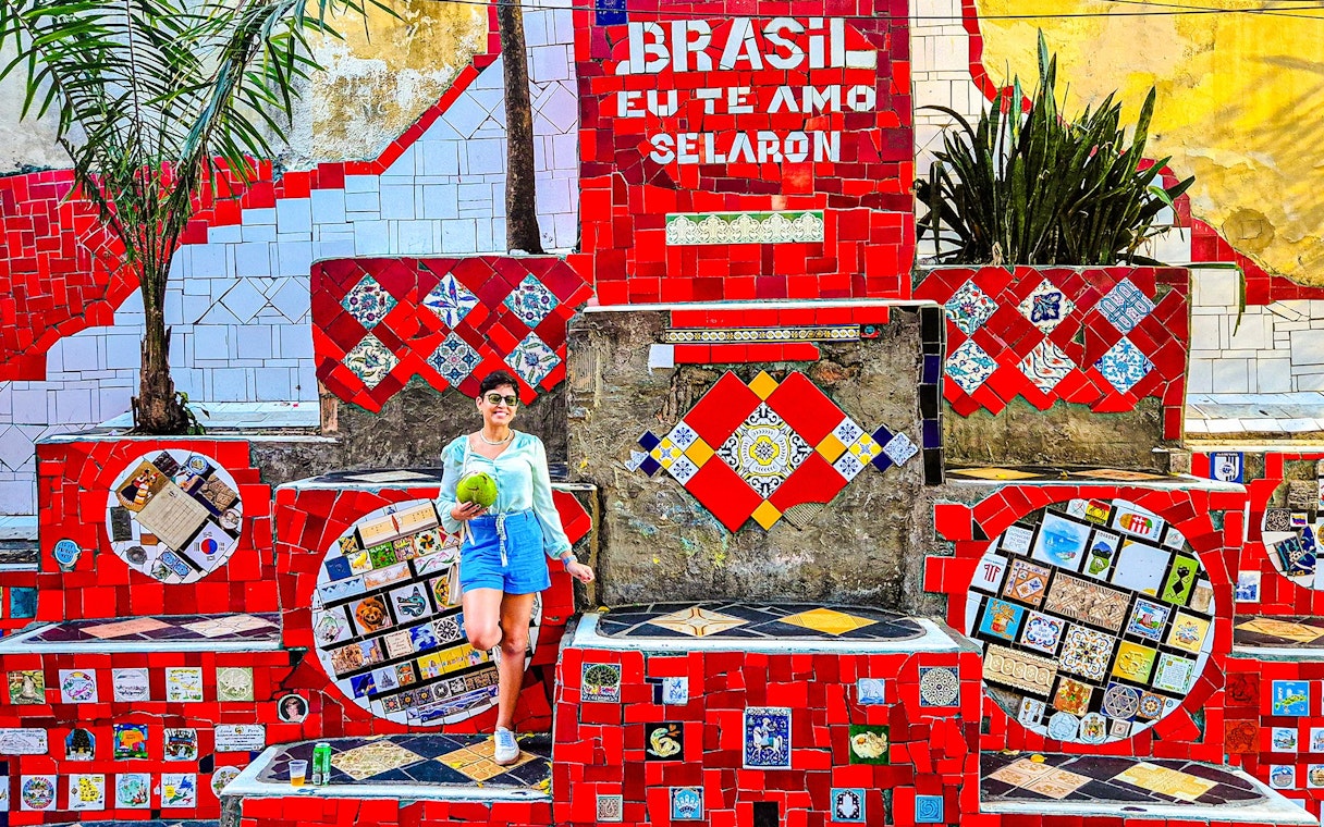 Tourist holding coconut at colorful Selaron Steps in Rio de Janeiro, Brazil.
