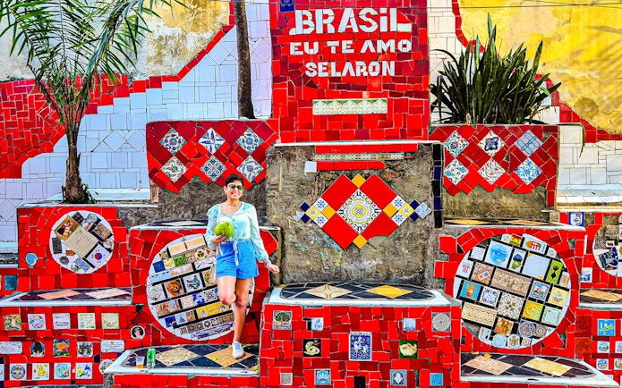 Tourist holding coconut at colorful Selaron Steps in Rio de Janeiro, Brazil.
