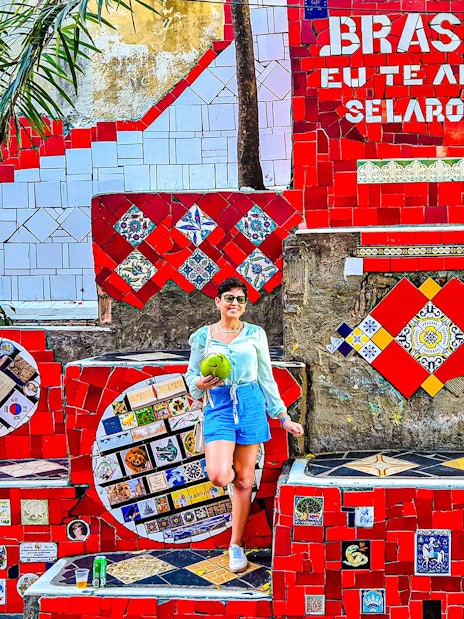 Tourist holding coconut at colorful Selaron Steps in Rio de Janeiro, Brazil.