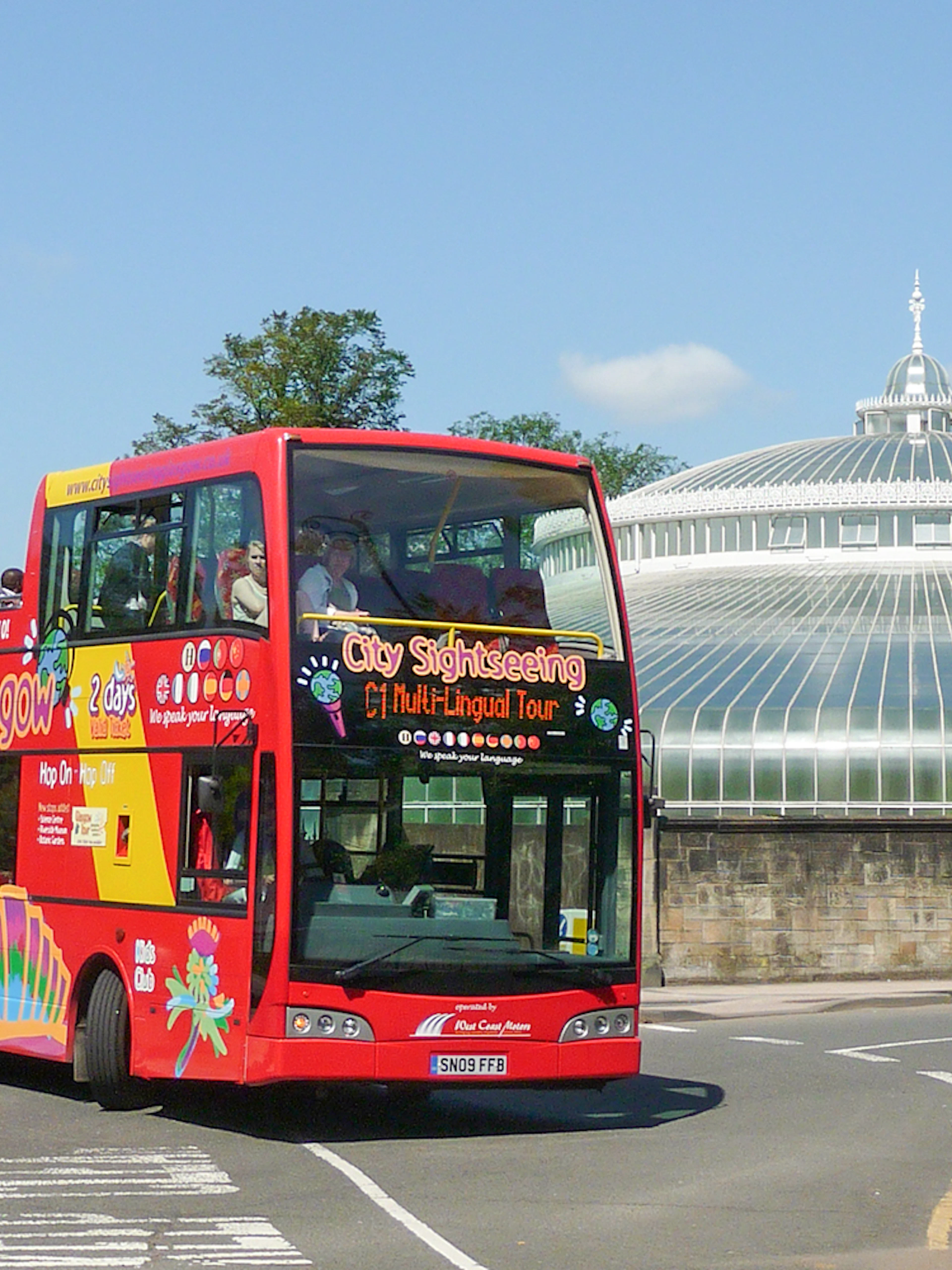 Red double-decker bus on Glasgow hop-on hop-off tour near the People's Palace.