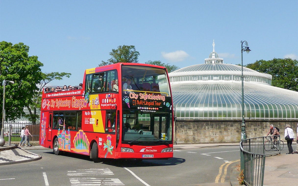 Red double-decker bus on Glasgow hop-on hop-off tour near the People's Palace.