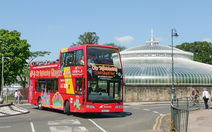 Red double-decker bus on Glasgow hop-on hop-off tour near the People's Palace.
