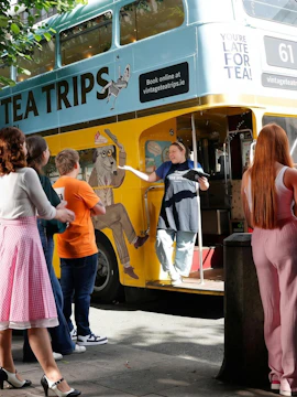 Afternoon tea bus tour in Dublin with guide welcoming passengers aboard vintage double-decker.