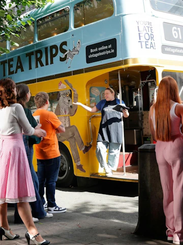 Afternoon tea bus tour in Dublin with guide welcoming passengers aboard vintage double-decker.
