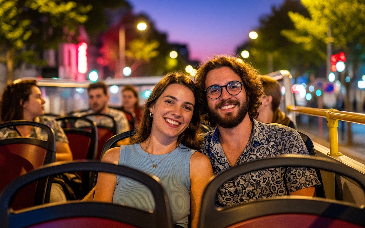 Tourists enjoying a city tour on a hop-on hop-off bus at dusk.