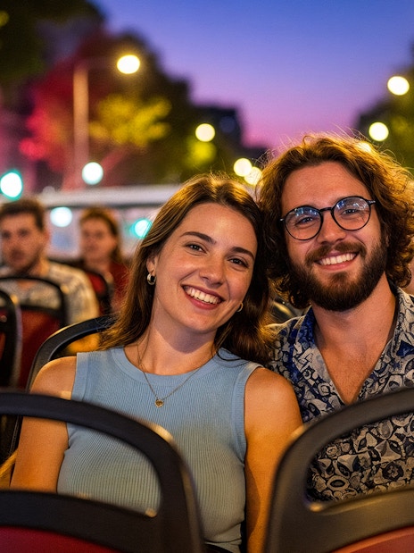 Tourists enjoying a city tour on a hop-on hop-off bus at dusk.