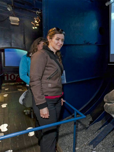 Visitor at Reykjavik whale exhibit with whale model and video display.