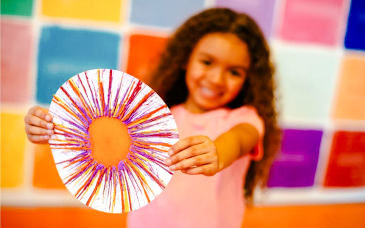 Child holding spin art creation at Crayola Experience, Mall of America.