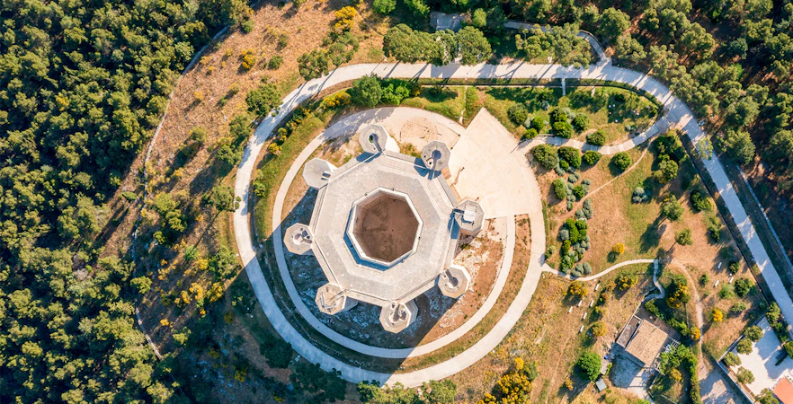 Aerial view of Castel del Monte's octagonal structure in Andria, Puglia, surrounded by greenery.