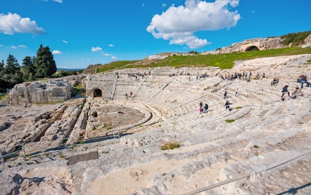Visitors exploring the ancient Greek Theater in Neapolis Archaeological Park, Syracuse.