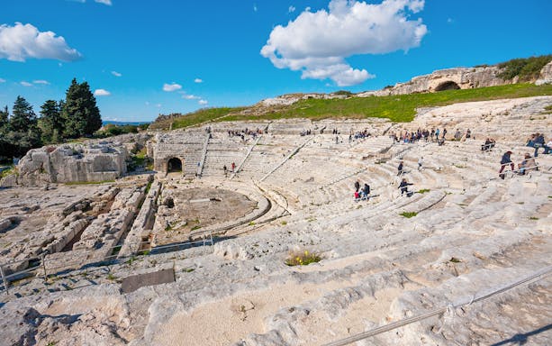 Visitors exploring the ancient Greek Theater in Neapolis Archaeological Park, Syracuse.