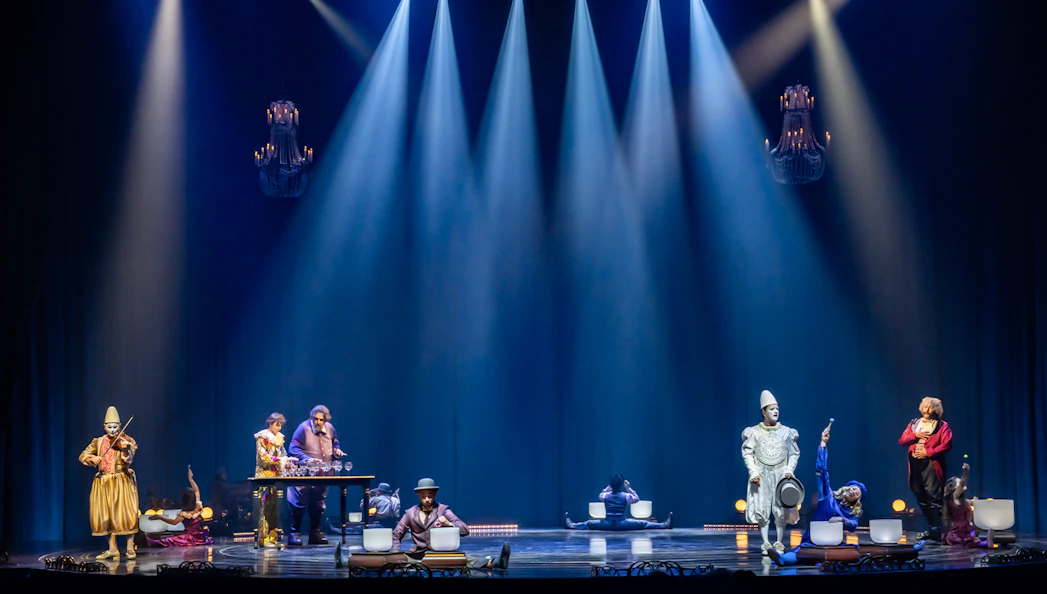 Performers on stage during Cirque du Soleil: Corteo, featuring musicians and acrobats under spotlights.
