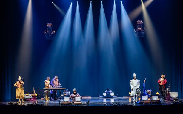 Performers on stage during Cirque du Soleil: Corteo, featuring musicians and acrobats under spotlights.