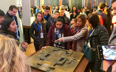Guide explaining Sagrada Familia Museum exhibit to a group of visitors.