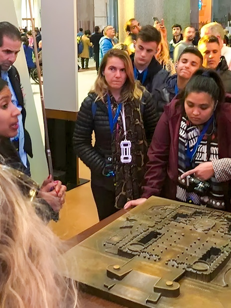 Guide explaining Sagrada Familia Museum exhibit to a group of visitors.