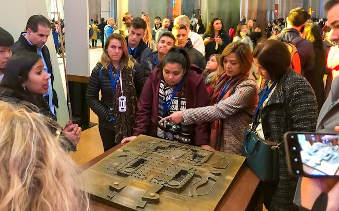 Guide explaining Sagrada Familia Museum exhibit to a group of visitors.
