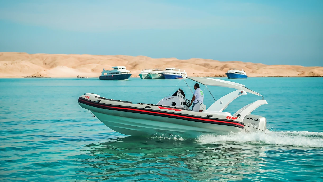 Private speedboat cruising near Orange Bay, Giftun Island, with distant yachts, Hurghada.