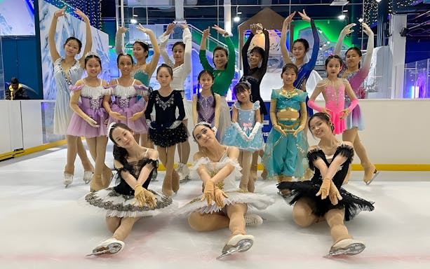 Ice skaters in colorful costumes posing at an indoor rink.