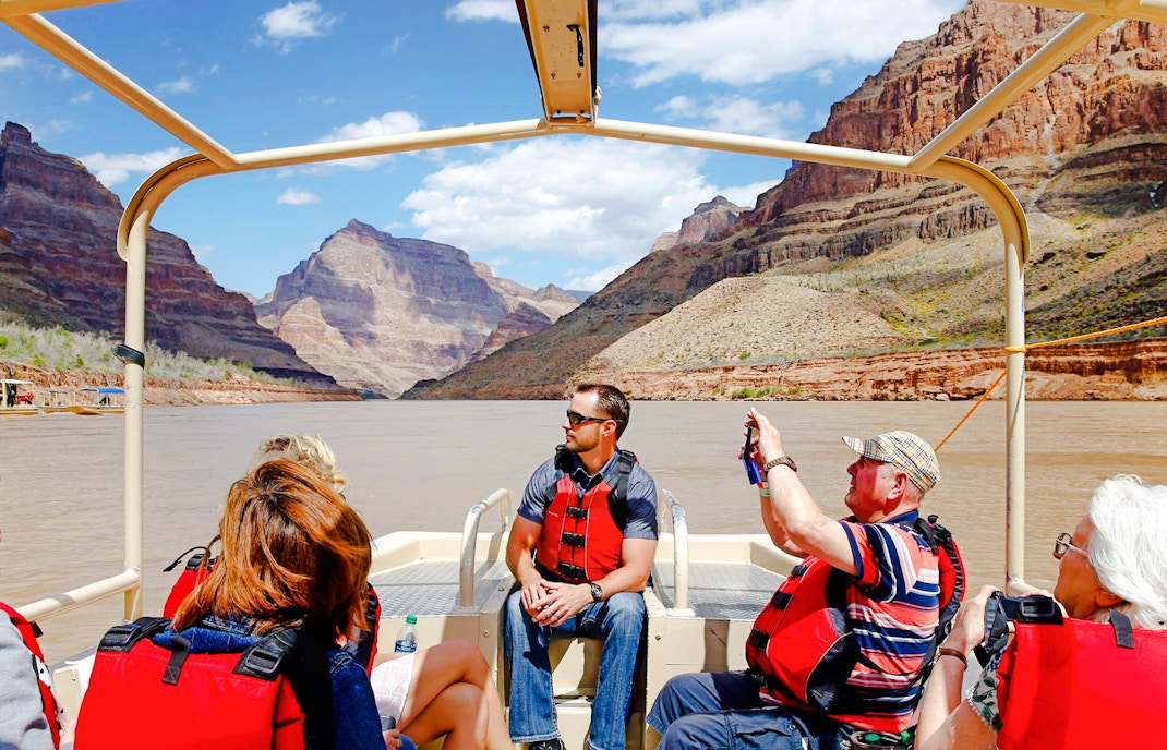 Guests on a boat tour at Grand Canyon West Rim with scenic views of canyon walls.