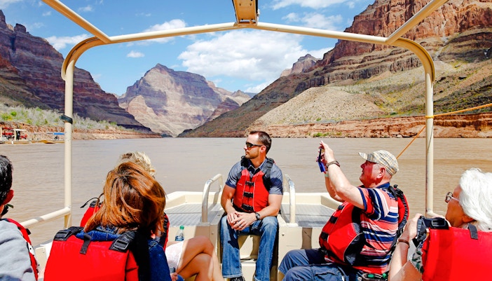 Guests on a boat tour at Grand Canyon West Rim with scenic views of canyon walls.