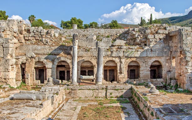 Ancient Fountain of Peirene ruins with stone arches and columns in Corinth, Greece.