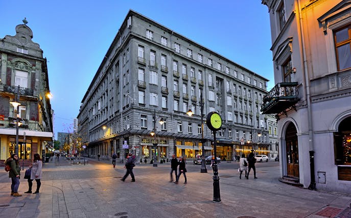 Street view in Łódź with historic buildings and people walking, part of guided tour from Warsaw.