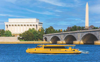 Yellow water taxi on Potomac River with Lincoln Memorial and Washington Monument in background.