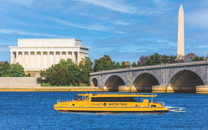 Yellow water taxi on Potomac River with Lincoln Memorial and Washington Monument in background.