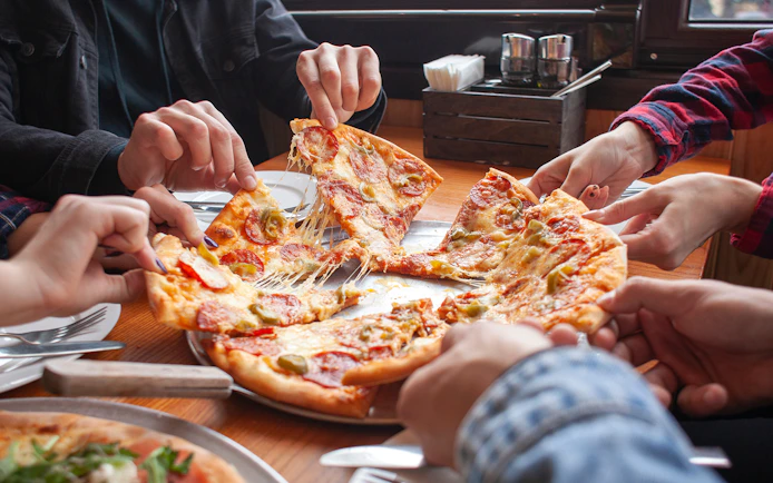 Group sharing pizza at a restaurant in Milano Bovisa.