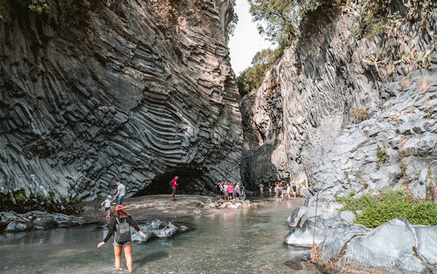 People trekking through the rocky Alcantara Gorge in Sicily, Italy.