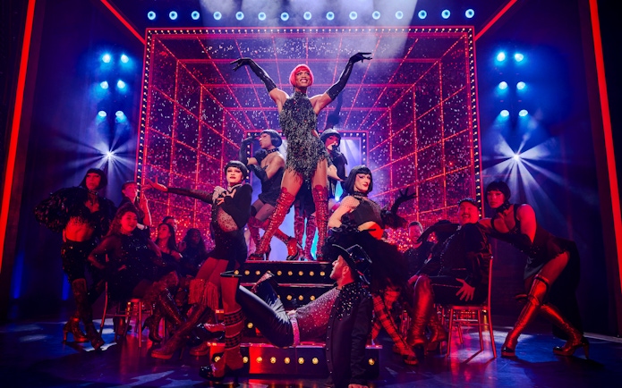 Performers in vibrant costumes on stage during a Kinky Boots production.