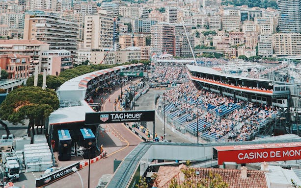 Monaco Grand Prix racetrack with crowded stands and cityscape in the background.