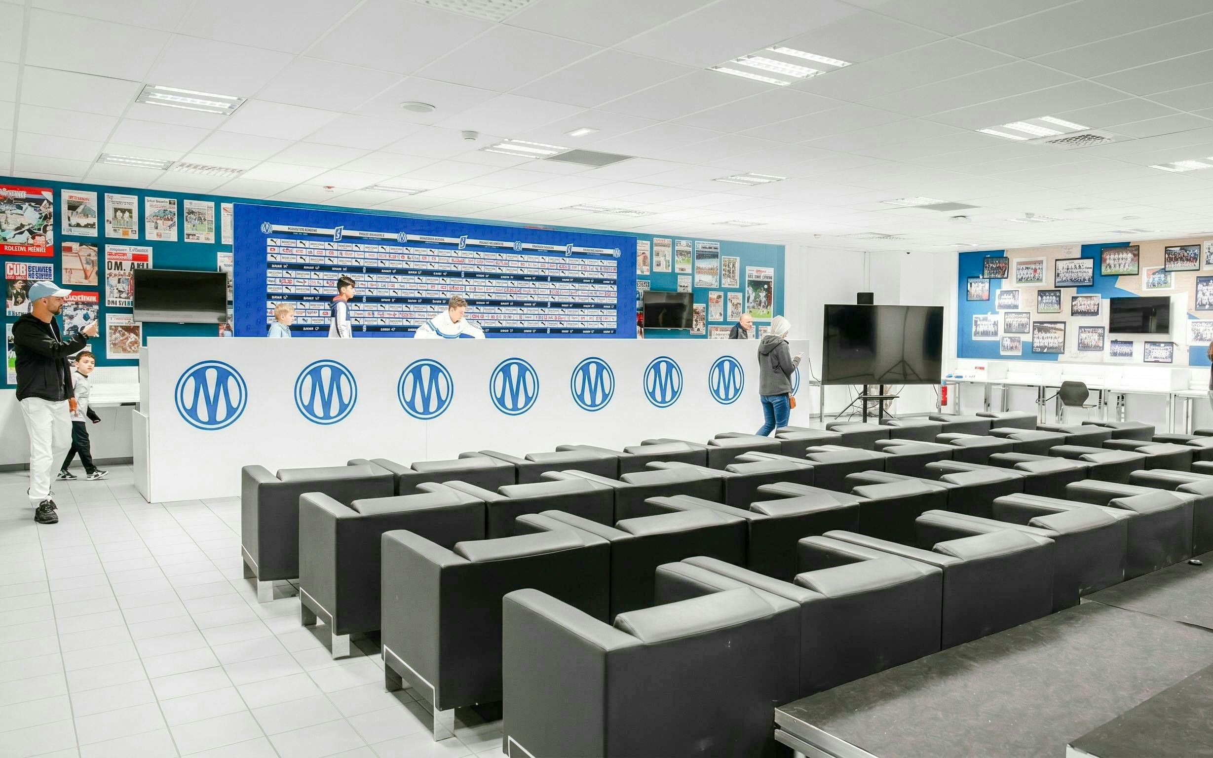 Press room at OM Stadium with seating and backdrop for interviews.