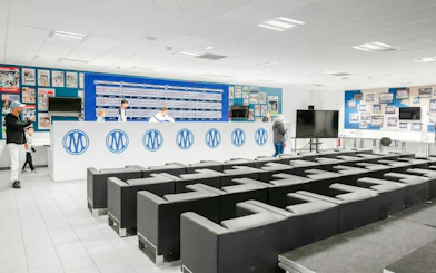 Press room at OM Stadium with seating and backdrop for interviews.