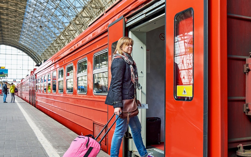 Women boarding Zermatt shuttle train with luggage at station.