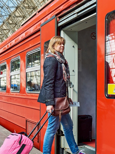 Women boarding Zermatt shuttle train with luggage at station.